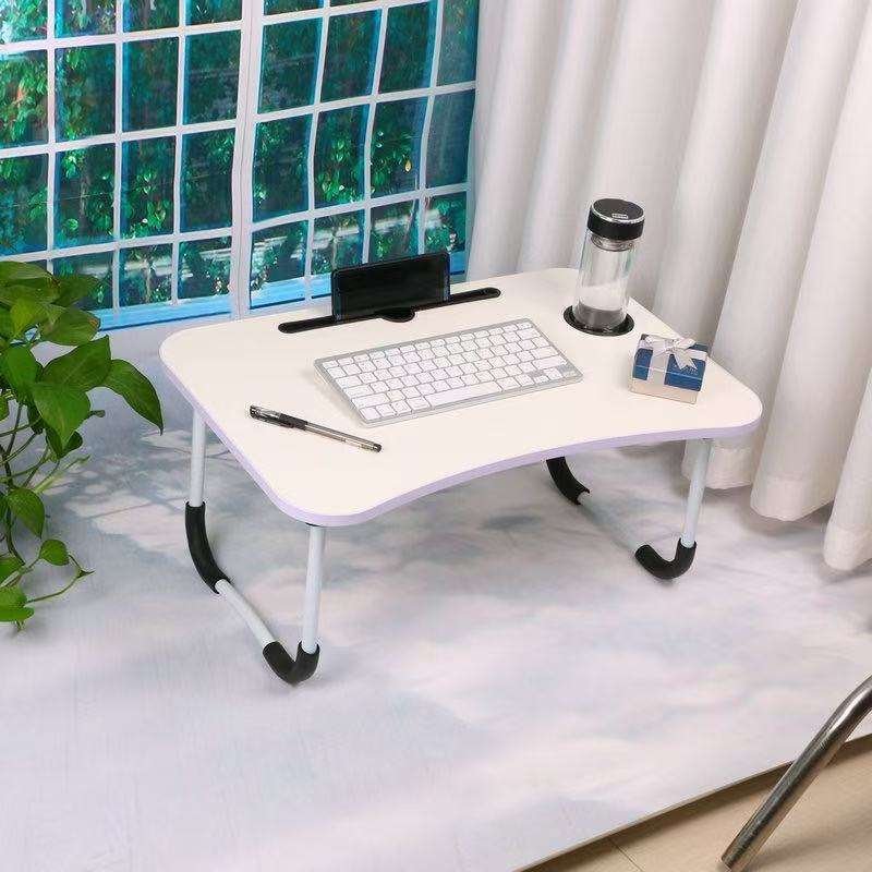 Bureau pliable Workphile déplié près d'une fenêtre, avec clavier, support téléphone et porte-gobelet.